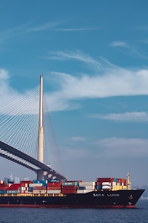 a large cargo ship passing under a bridge