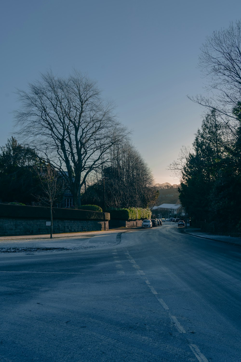 a street with snow on the ground and trees in the background