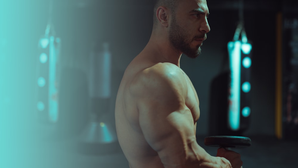 a shirtless man holding a barbell in a gym