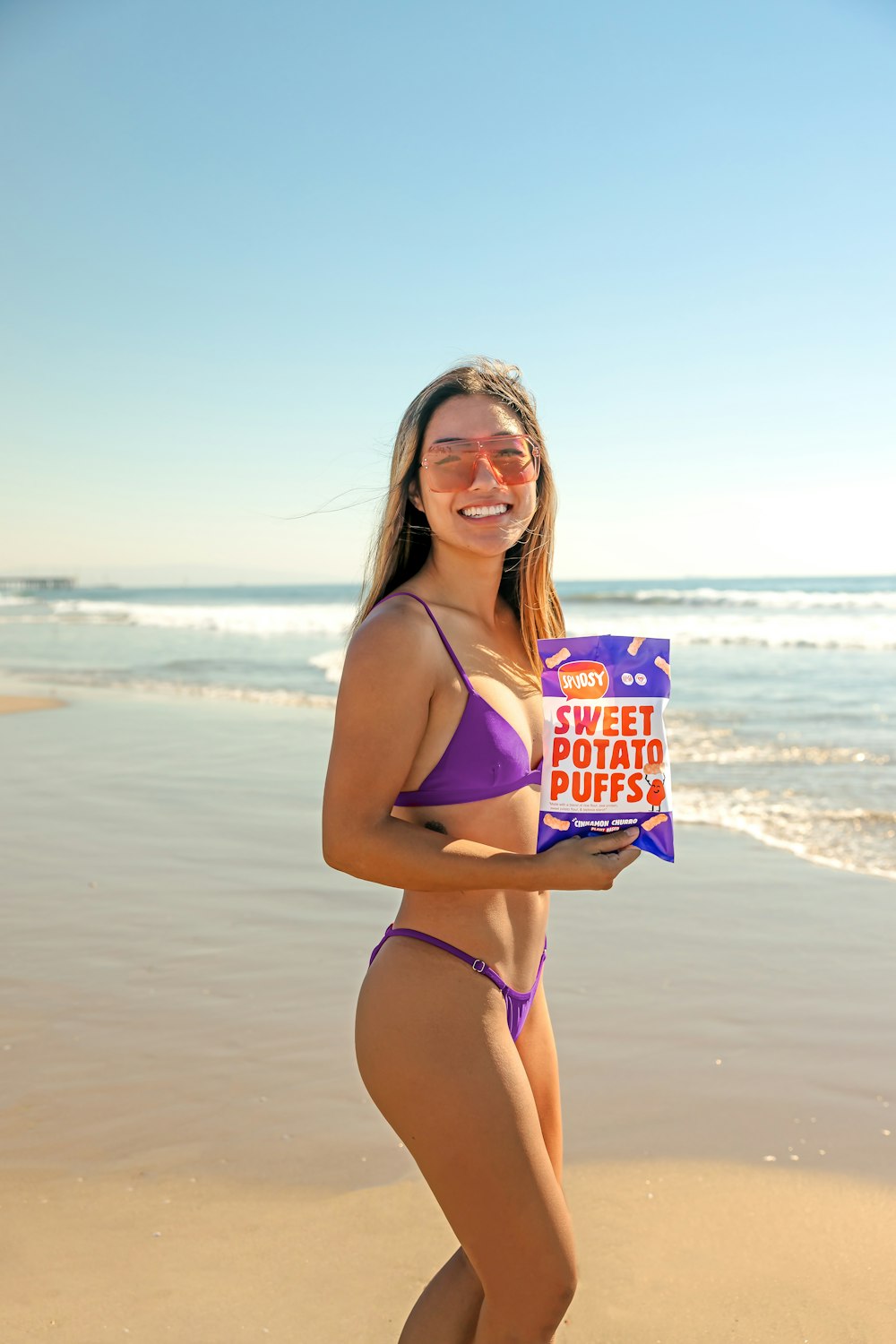 a woman in a bikini holding a box of potato chips