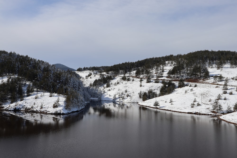 Un lago rodeado de colinas cubiertas de nieve y árboles