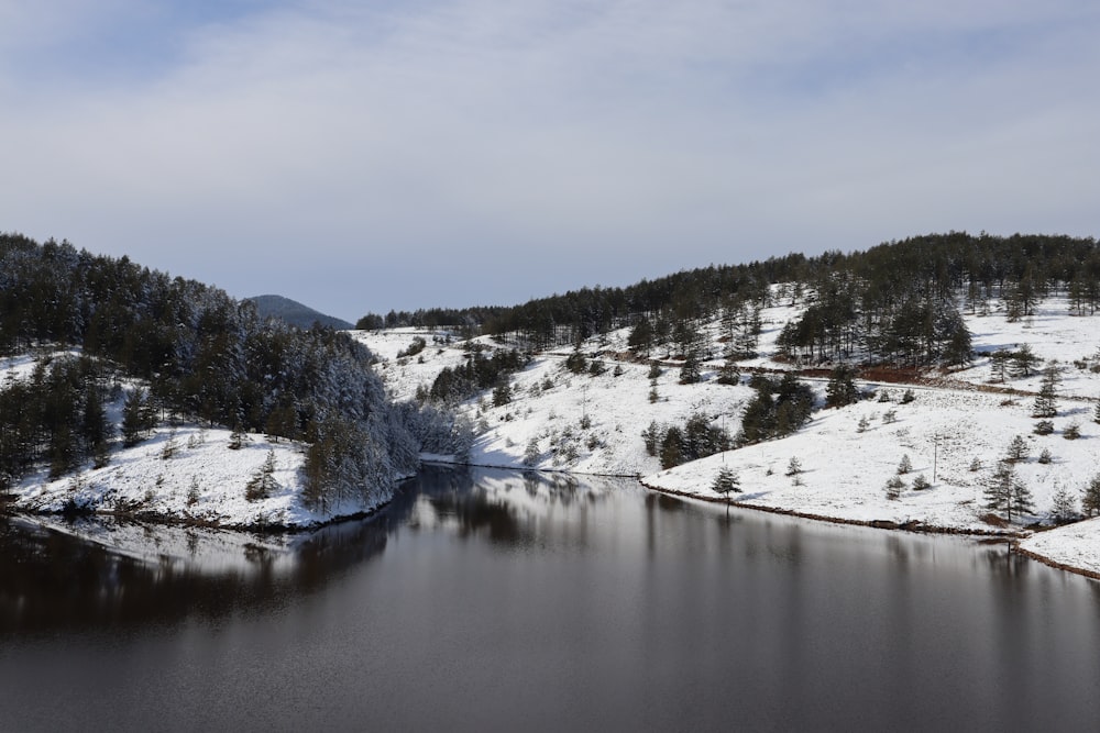 um lago cercado por colinas cobertas de neve e árvores