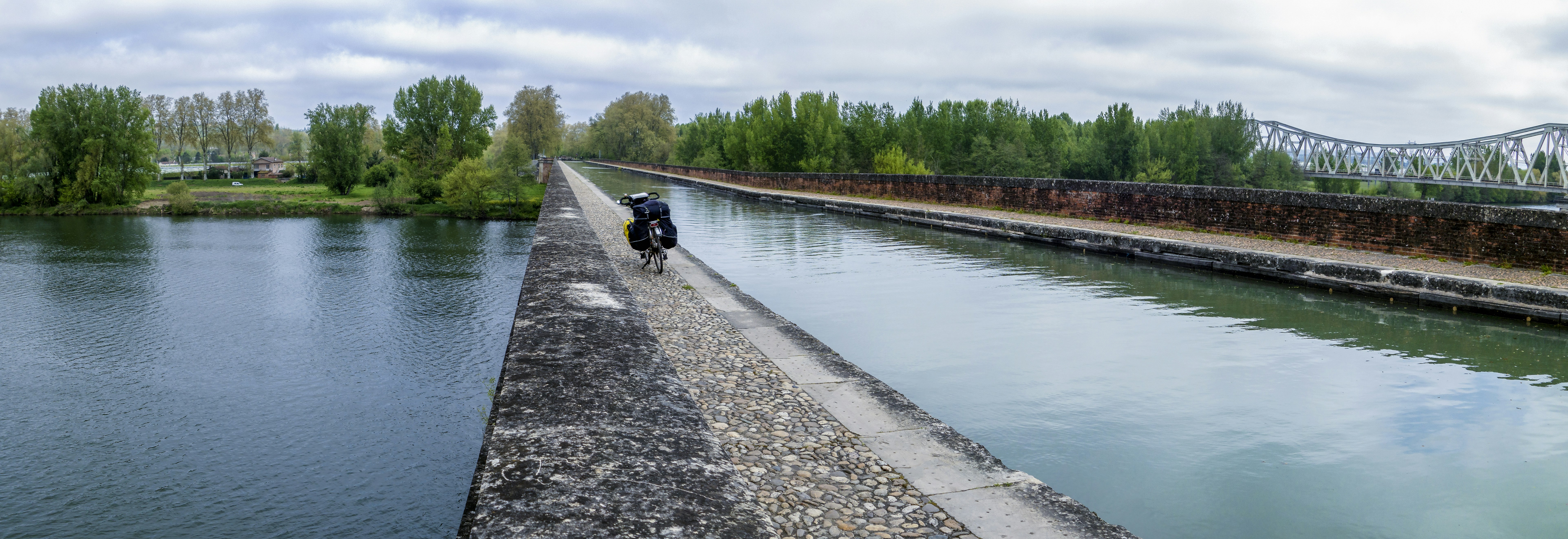 Man riding motorcycle down river next to bridge