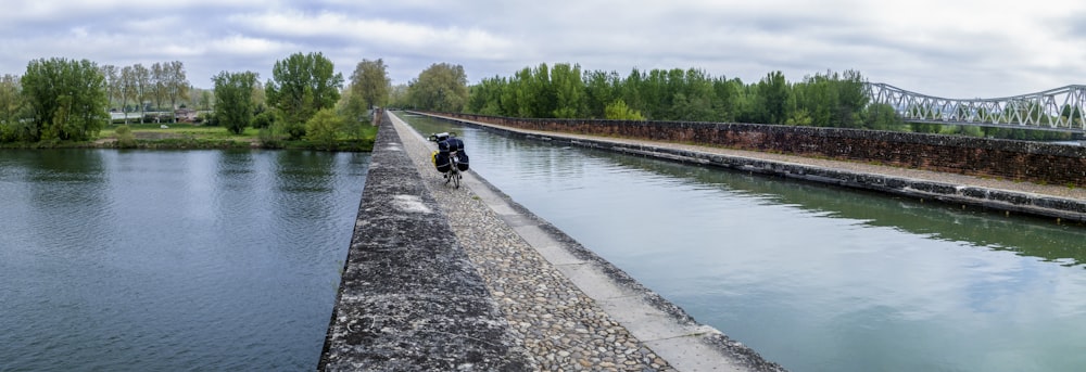 a man riding a motorcycle down a river next to a bridge