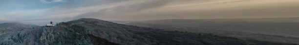 A panoramic shot capturing the foggy landscape and farmhouse plots of Gorthan at dawn.