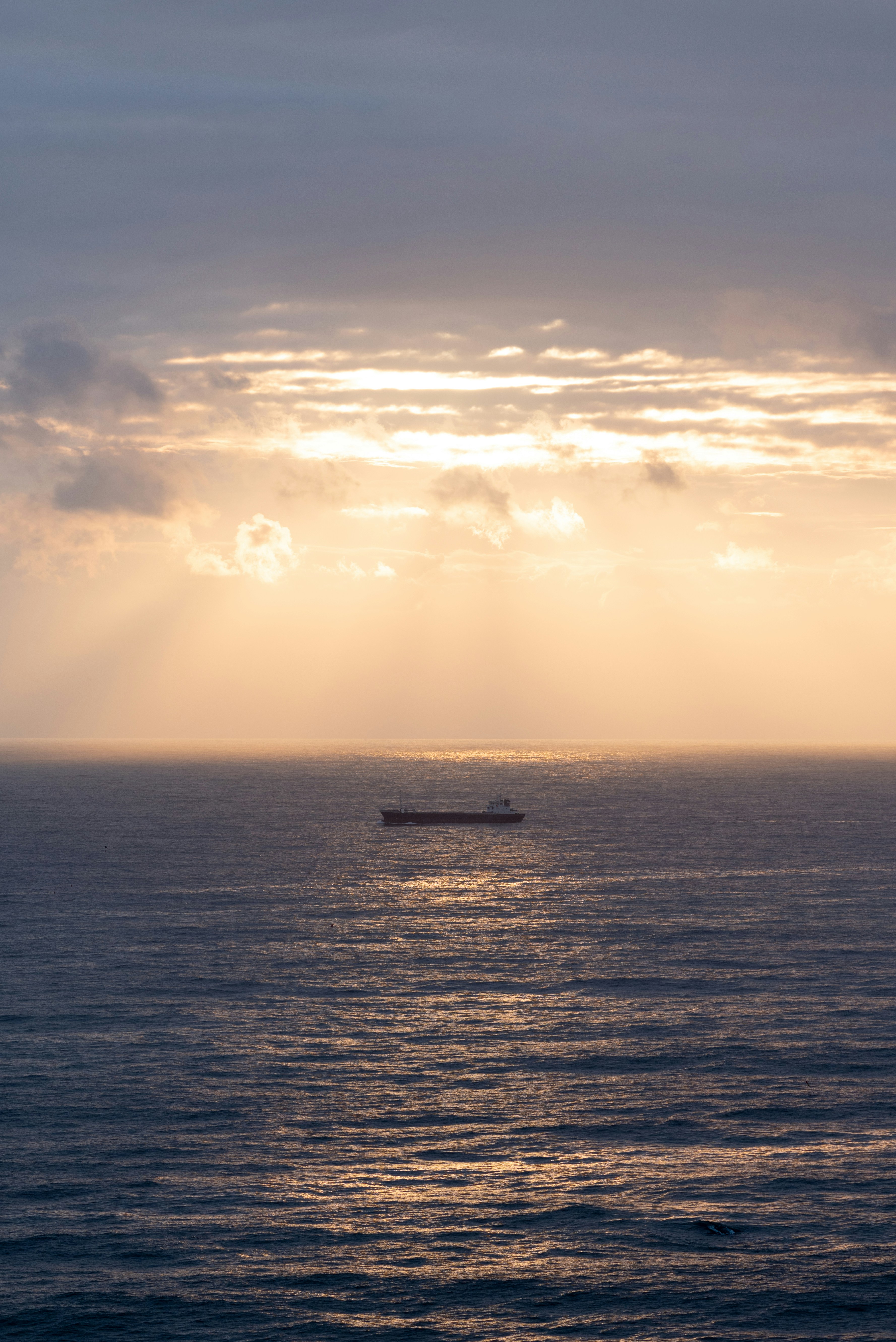 a boat in the middle of the ocean under a cloudy sky