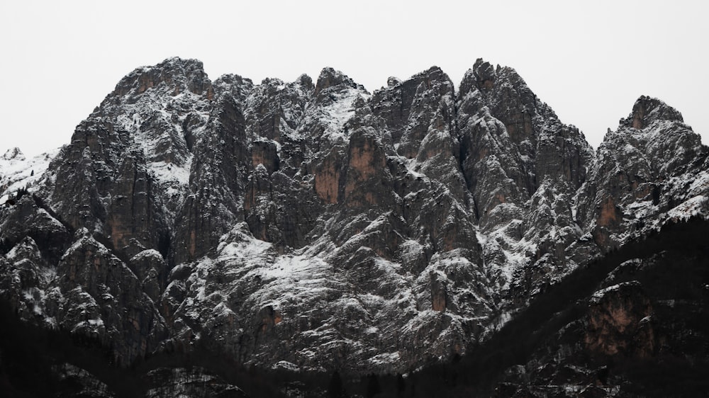 a snow covered mountain range with trees in the foreground