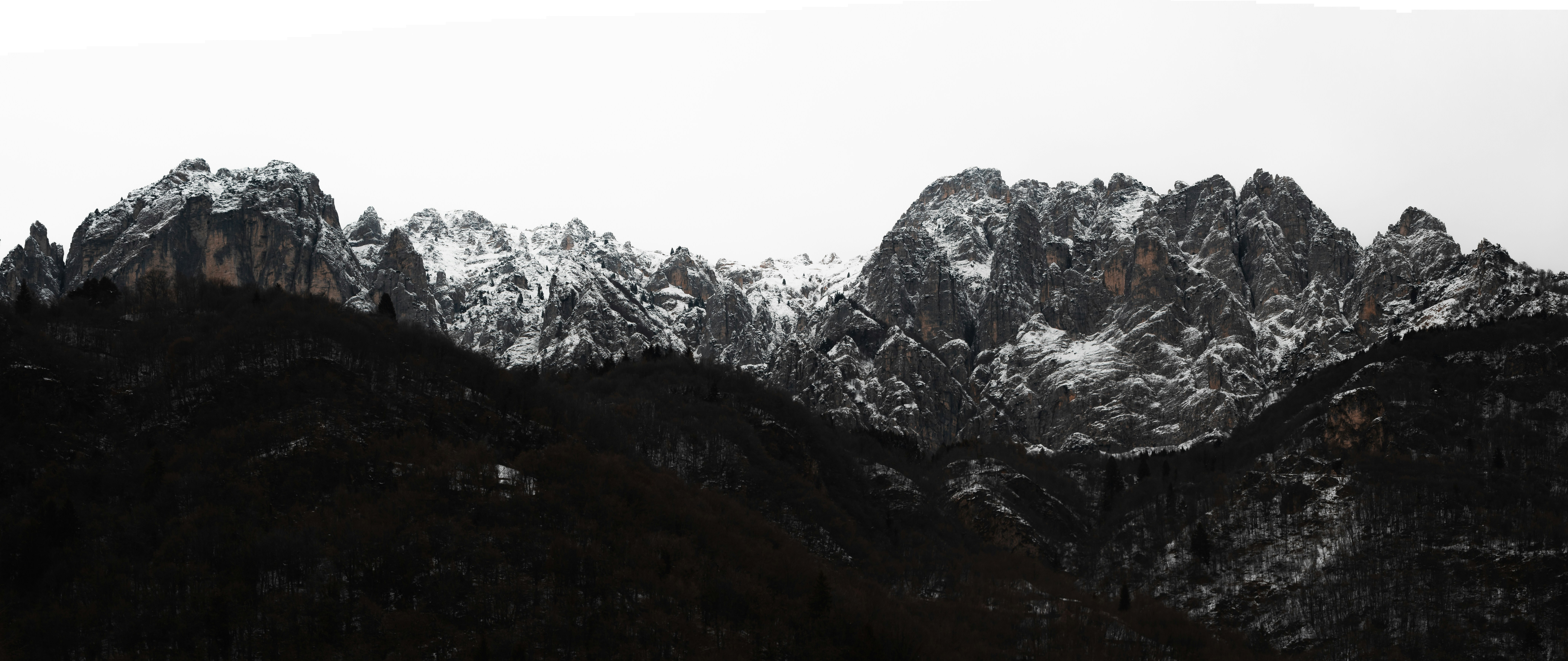 A mountain range covered in snow with mountains in the background photo ...