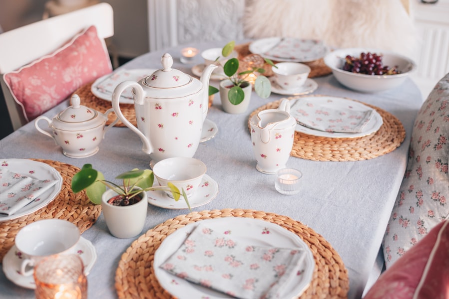 Elegant tea party table setting with vintage plates, cups, candles, and fresh plants