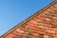 Close-up of a neatly installed dry ridge on a sloped roof under a clear blue sky.