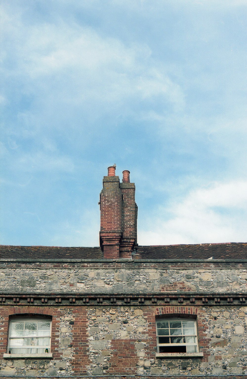 a brick building with two chimneys and a sky background