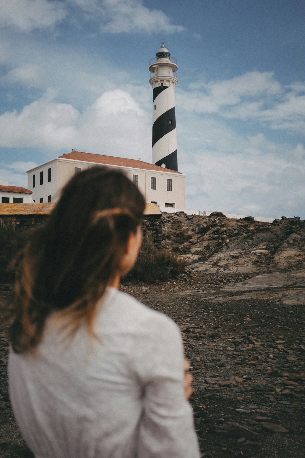 a woman standing in front of a lighthouse