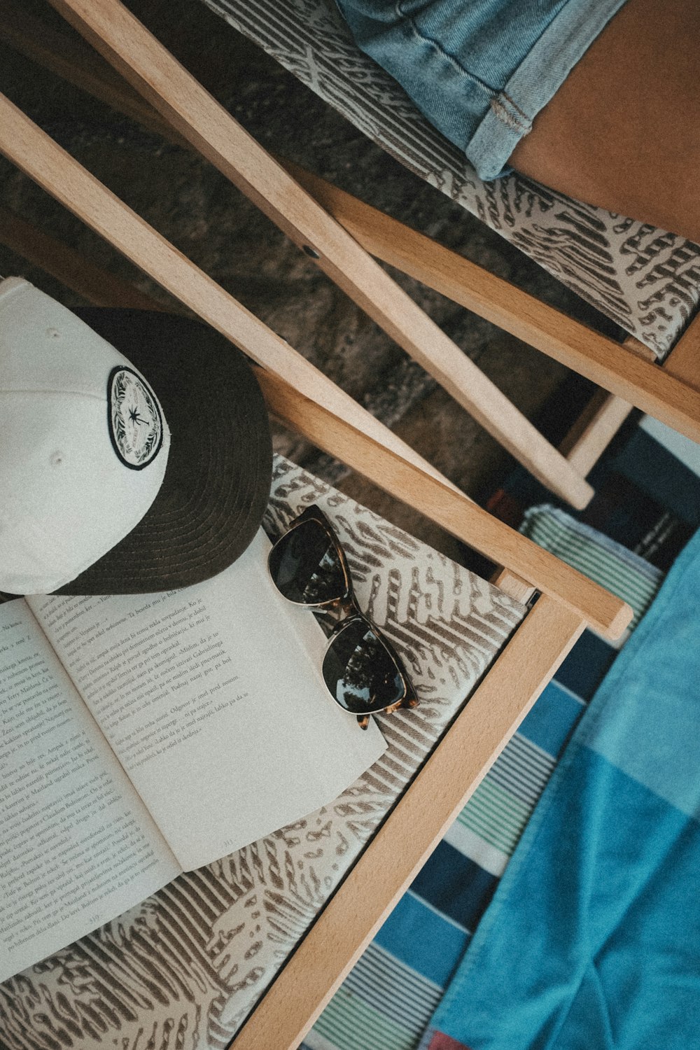 a hat, sunglasses, and book on a bed