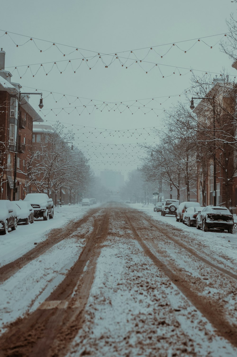 a snowy street with cars parked on the side of it