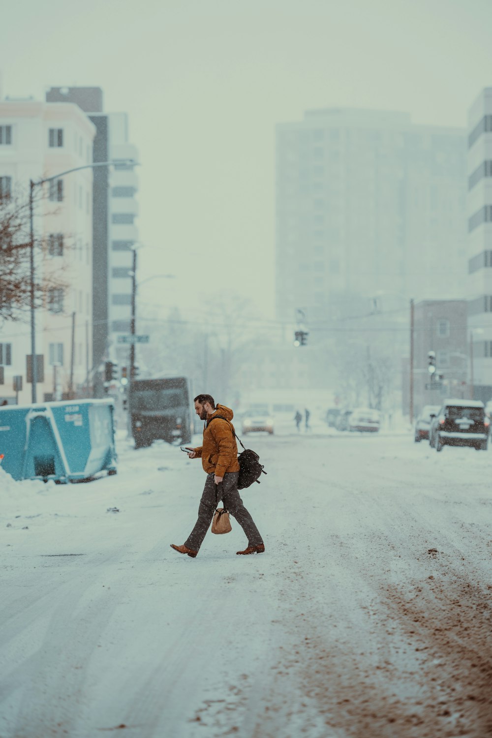 a man walking across a snow covered street