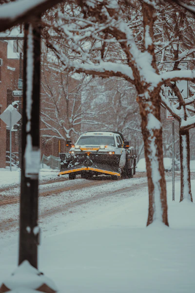 a snow plow is driving down a snowy street