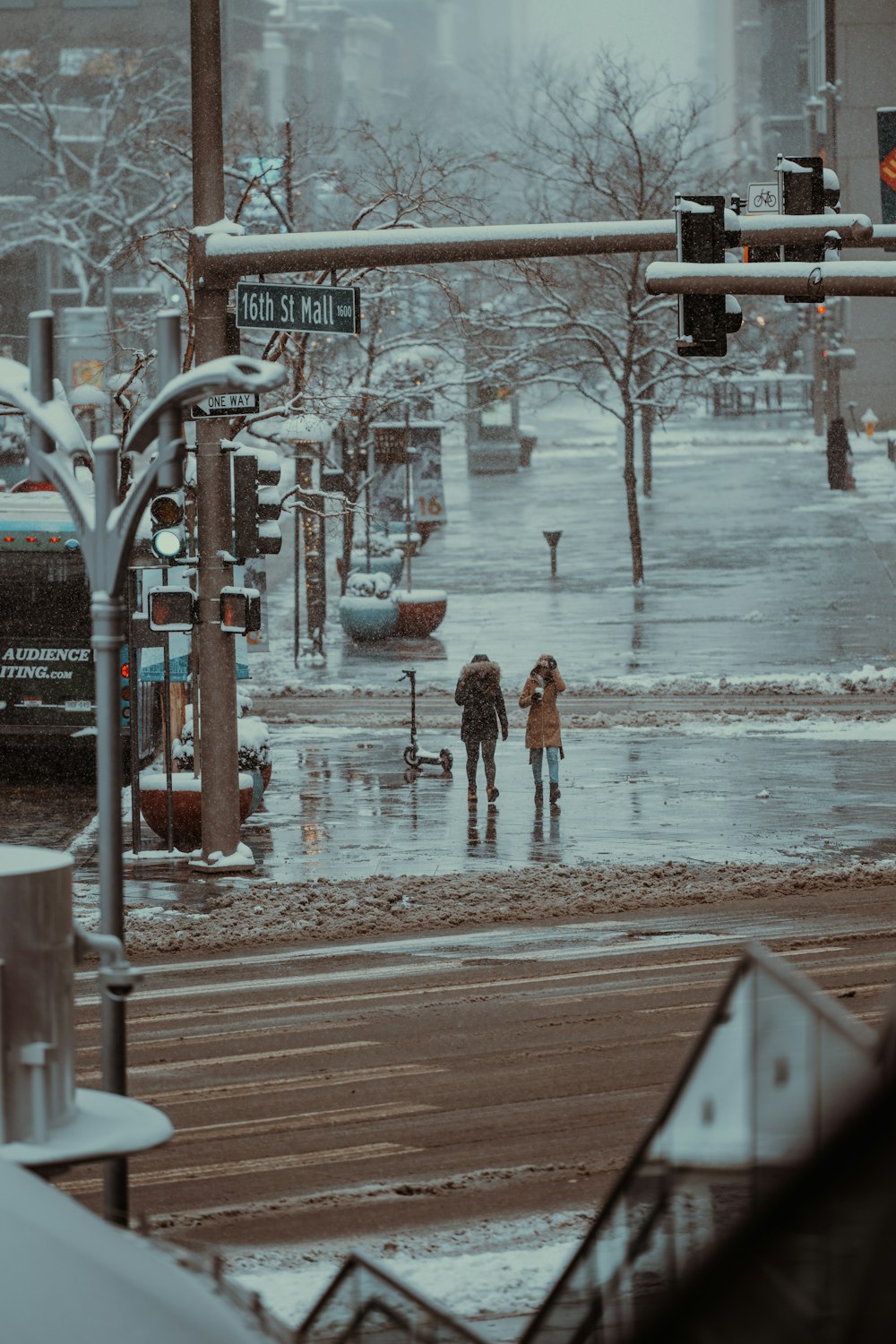 a couple of people walking across a street in the rain