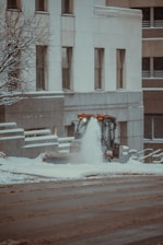 A snowplow clearing a busy street in a residential area.