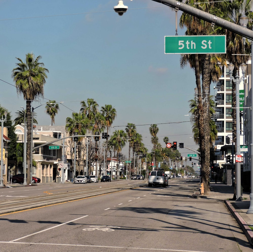 a street with palm trees and a street sign
