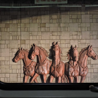 a group of horses standing next to a brick wall