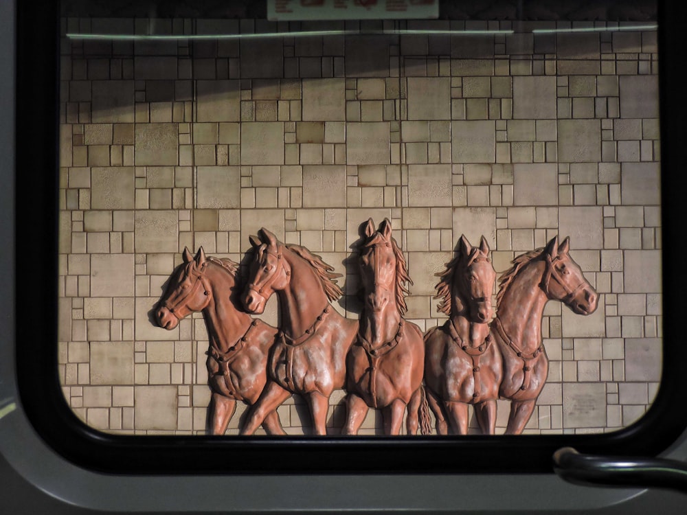 a group of horses standing next to a brick wall