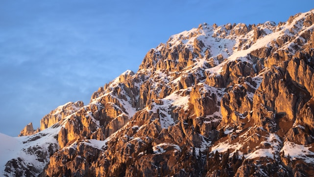 A panoramic view of rugged mountain peaks bathed in golden sunrise light