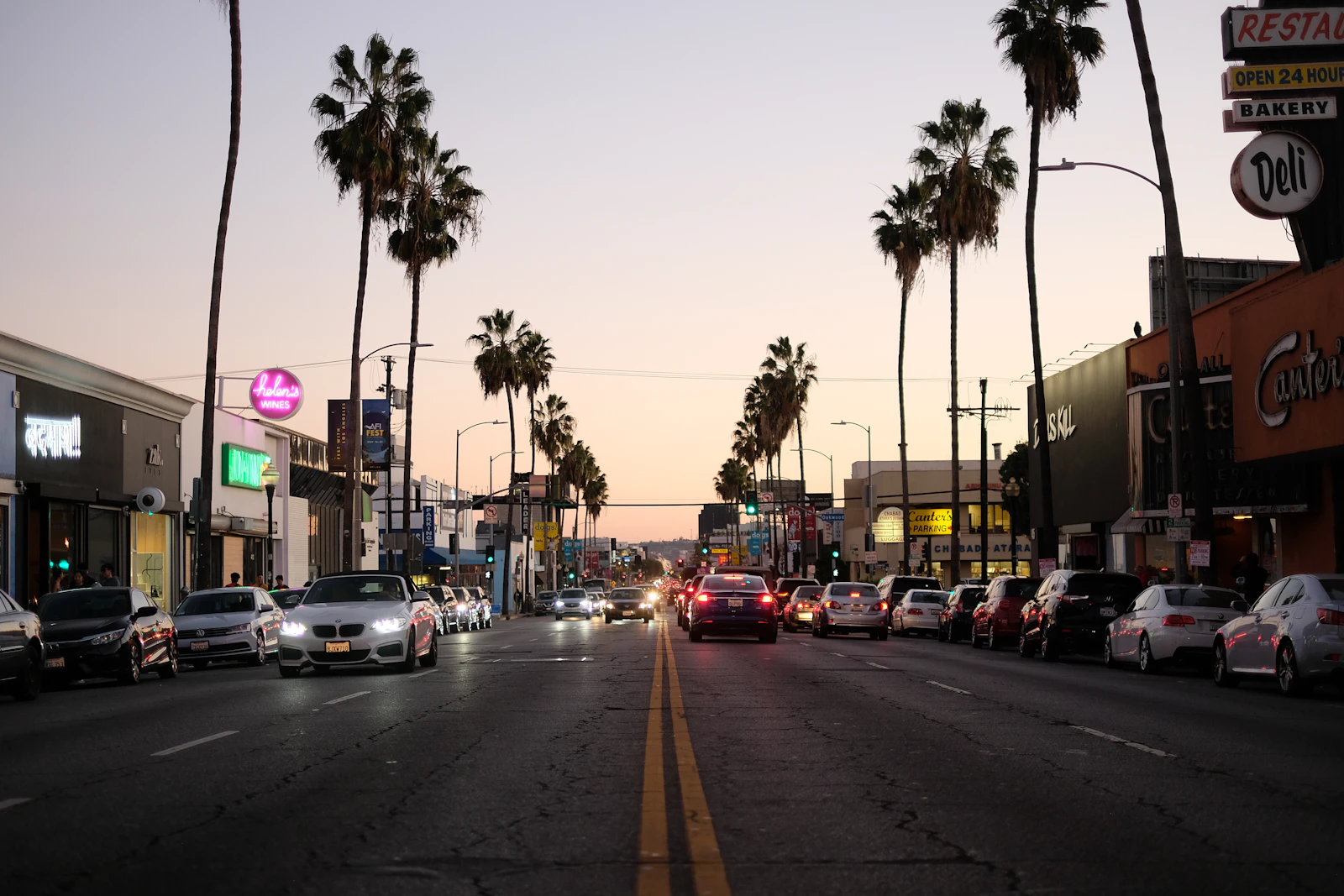 a street filled with lots of traffic next to tall palm trees