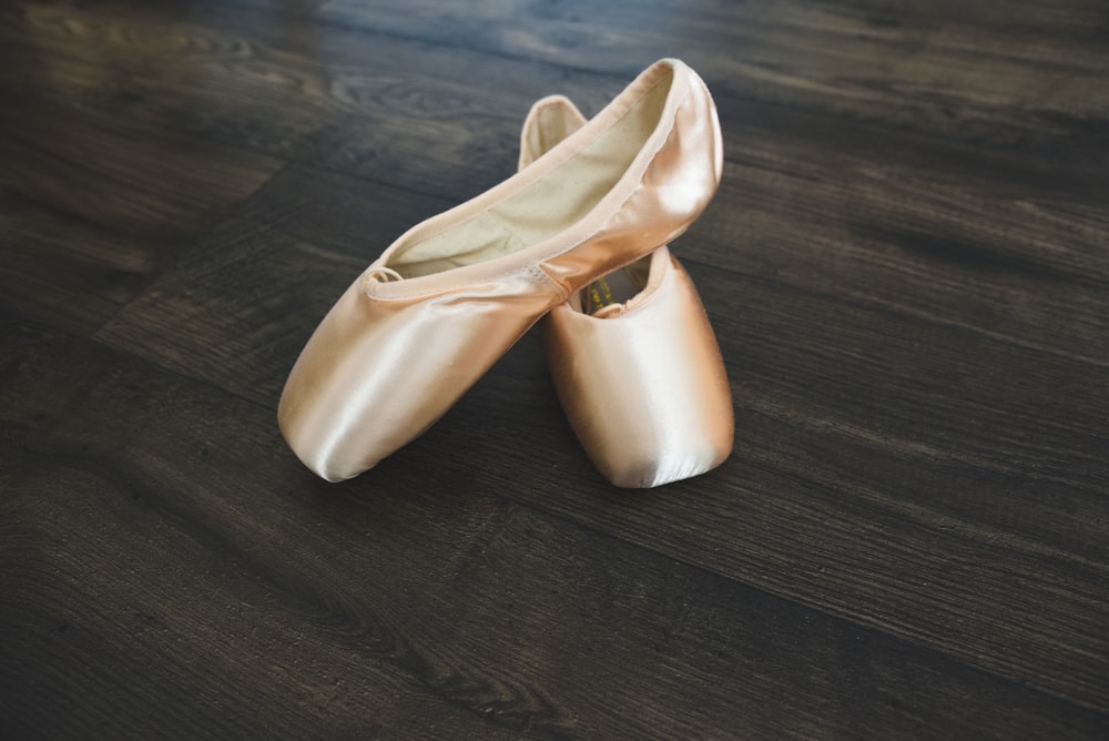 a pair of gold shoes sitting on top of a wooden floor