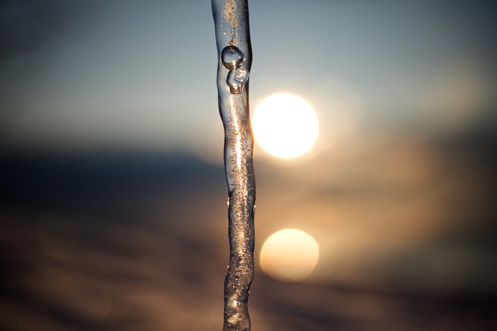 a close up of a water drop with the sun in the background