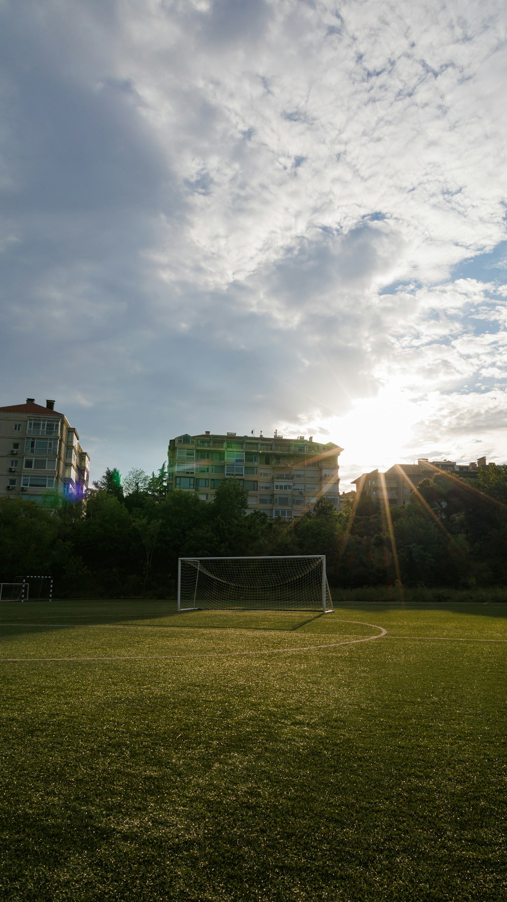 a soccer field with a soccer goal and buildings in the background