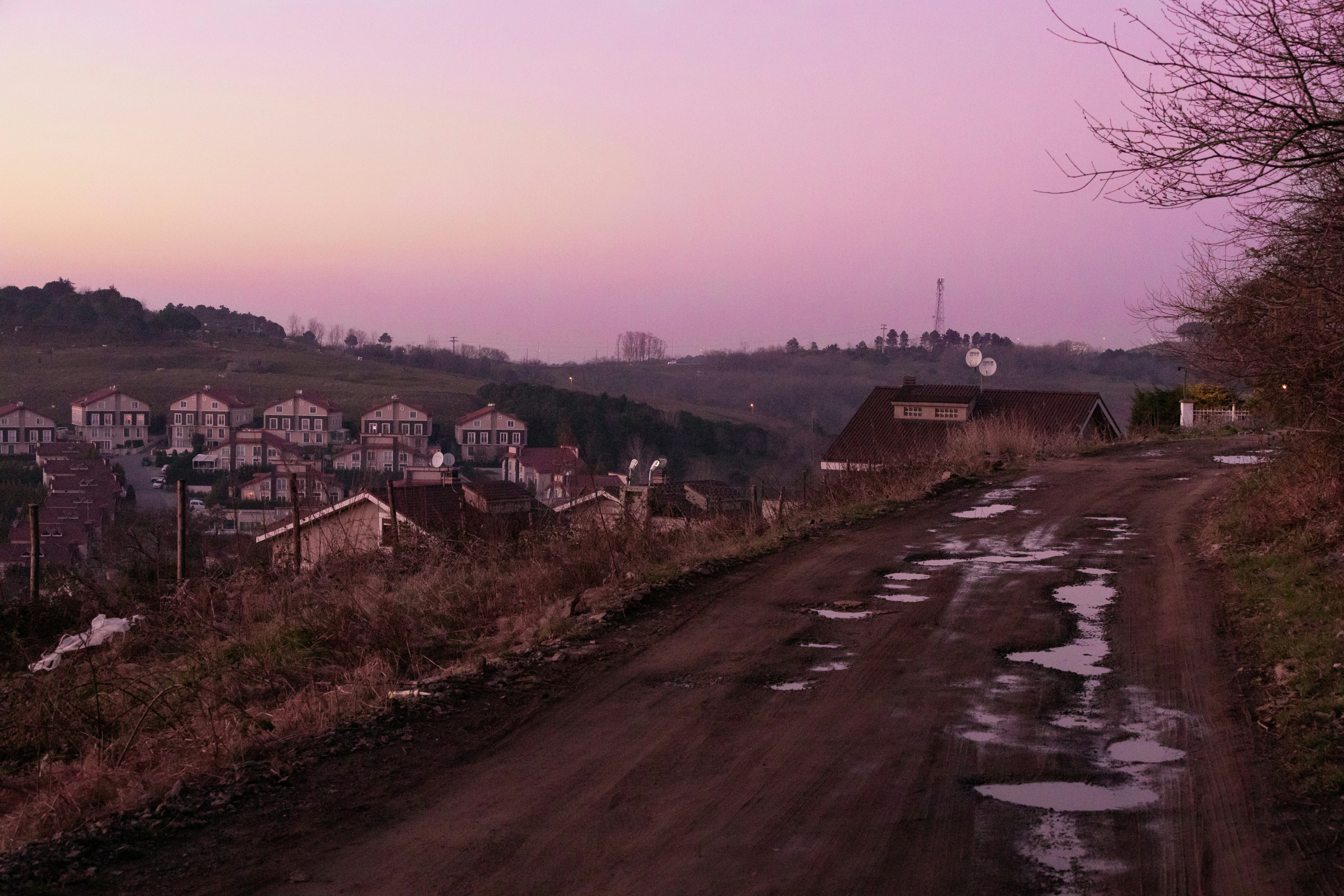 Eine unbefestigte Straße mit Häusern auf einem Hügel im Hintergrund