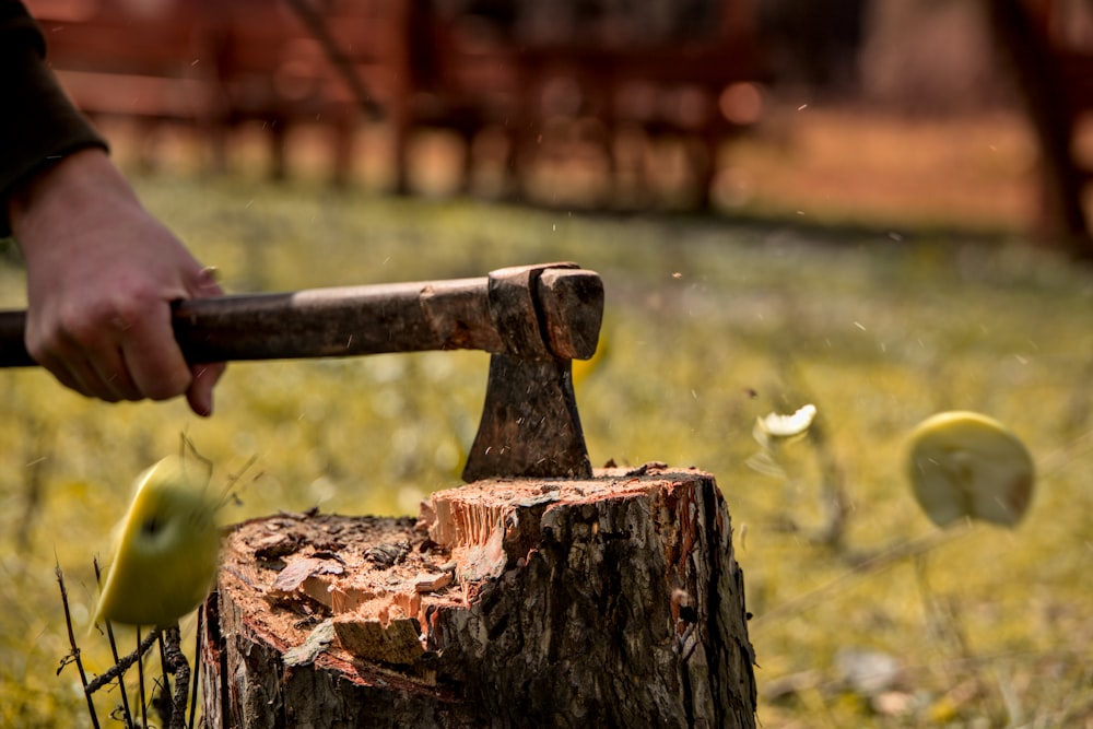 a person is holding a hammer over an apple