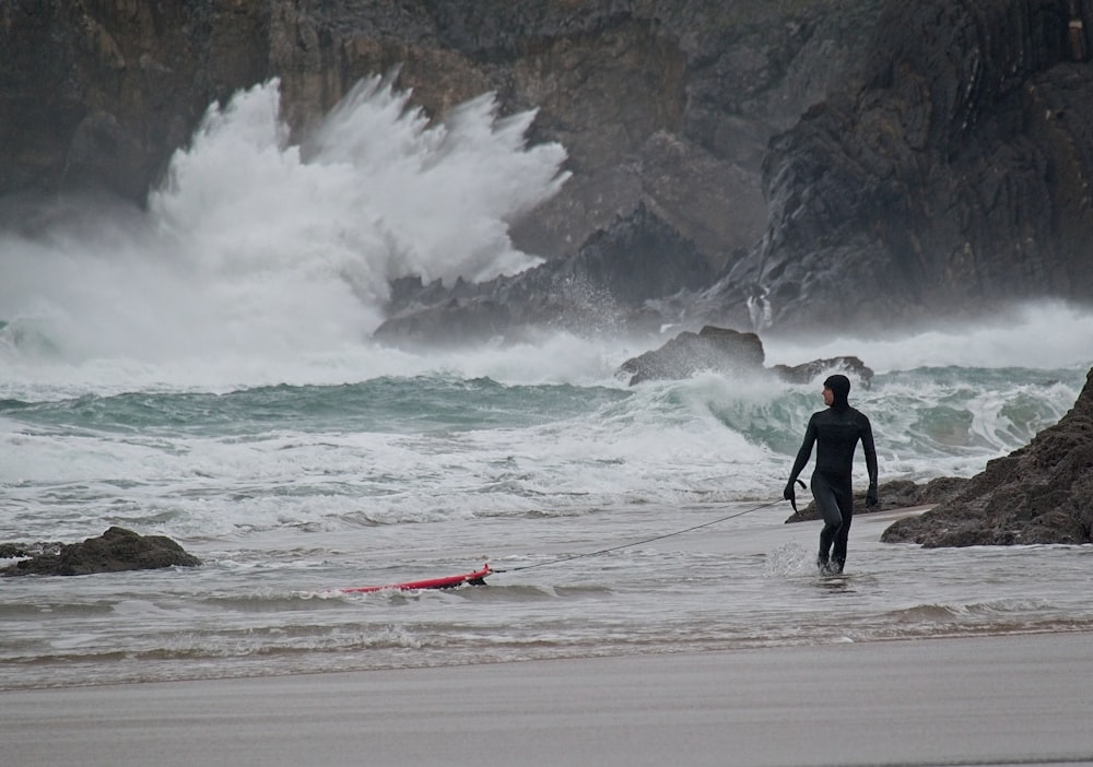 Un homme marchant sur la plage avec une planche de surf