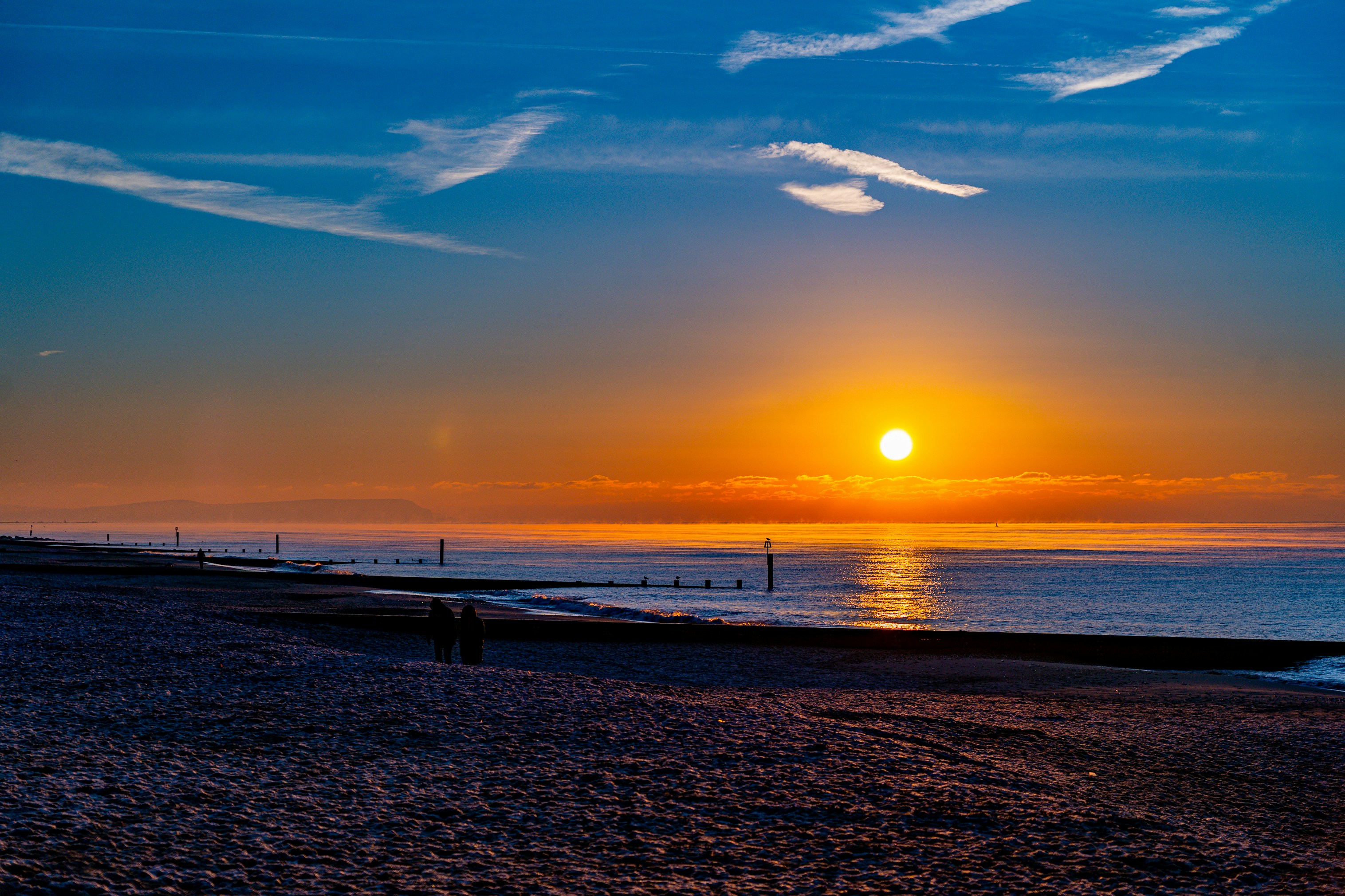 the sun is setting over the ocean on the beach