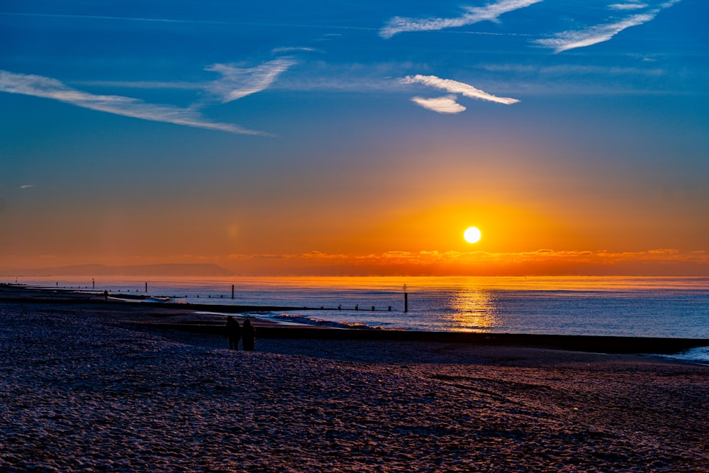 the sun is setting over the ocean on the beach