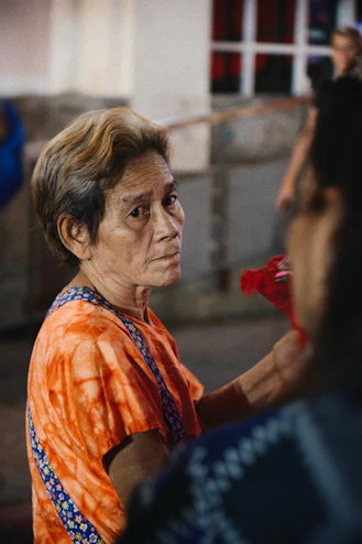 a woman in an orange shirt holding a red object