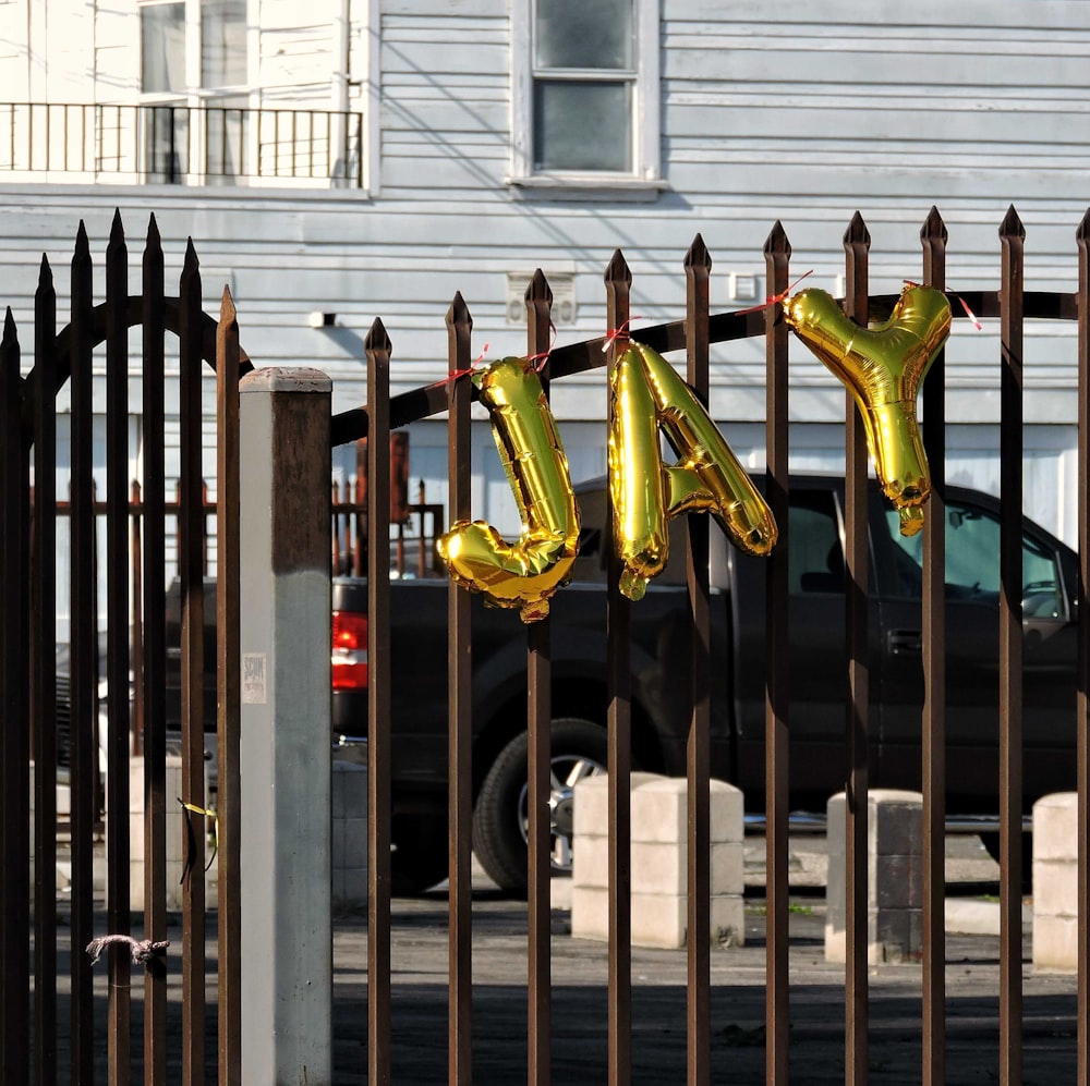 a car parked behind a fence with balloons in the shape of letters