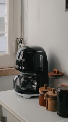 a black coffee maker sitting on top of a white counter