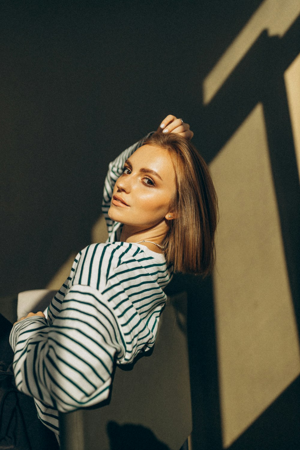 a woman standing in front of a wall with her hands on her head