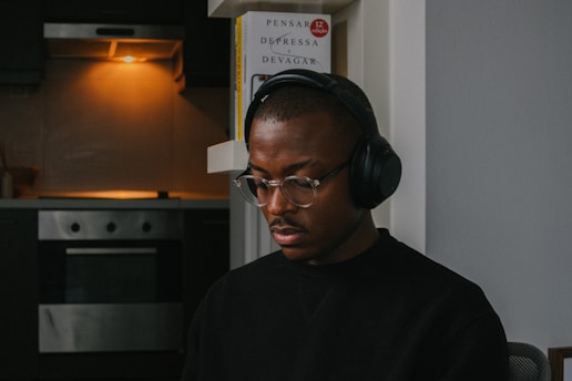 A person listening to headphones while reading a book in a cozy room.