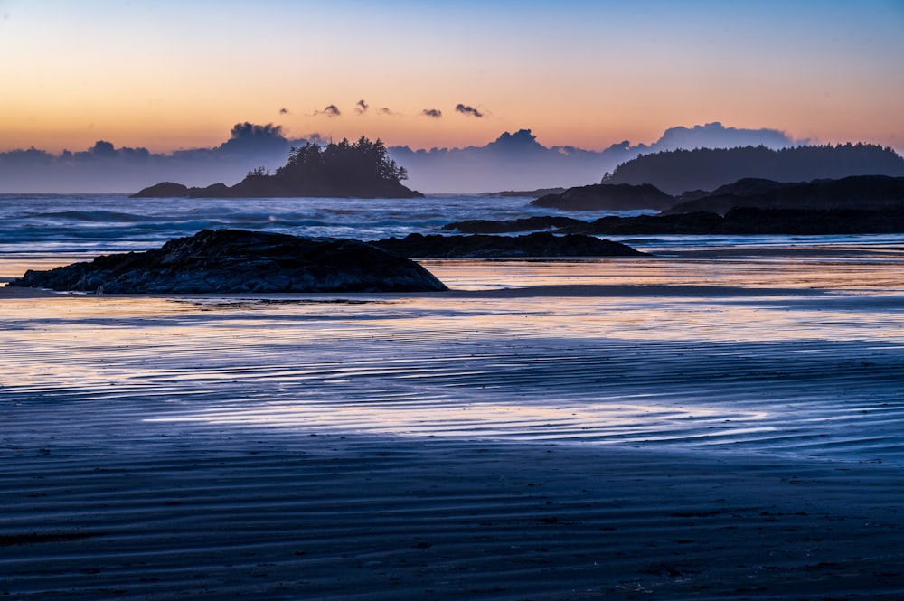 the sun is setting over the water at the beach