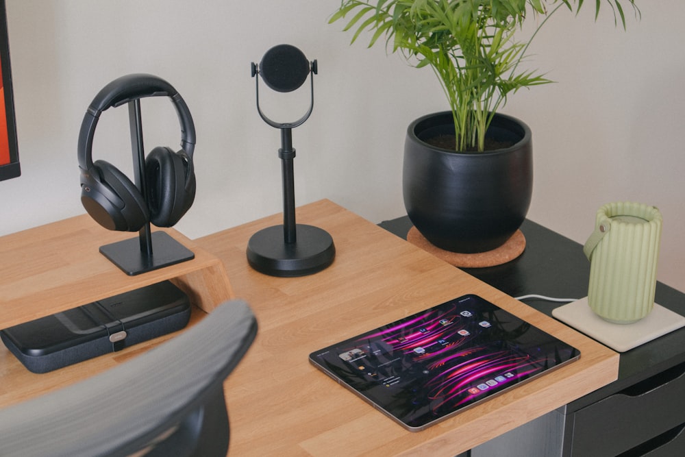 a desk with a cell phone, headphones and a plant