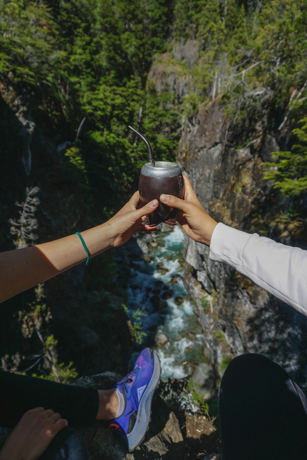 a couple of people holding onto a drink in front of a waterfall