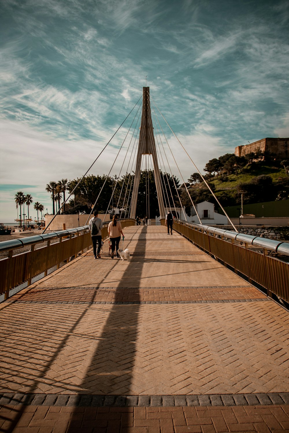 people walking across a bridge on a sunny day