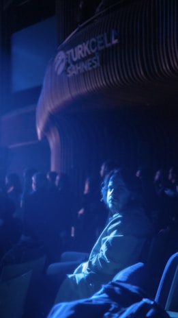 Ilker Karacam illuminated by warm stage lights, eyes closed in emotional moment