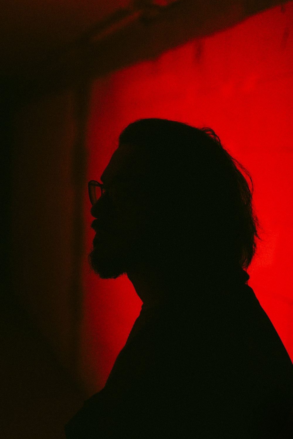 a silhouette of a man with glasses against a red background