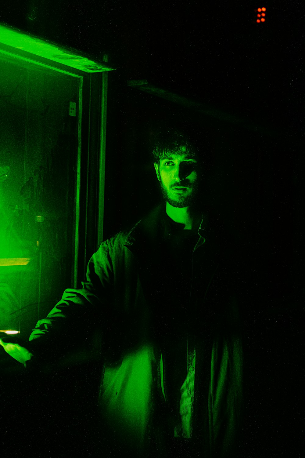 a man standing in a dark room with a green light