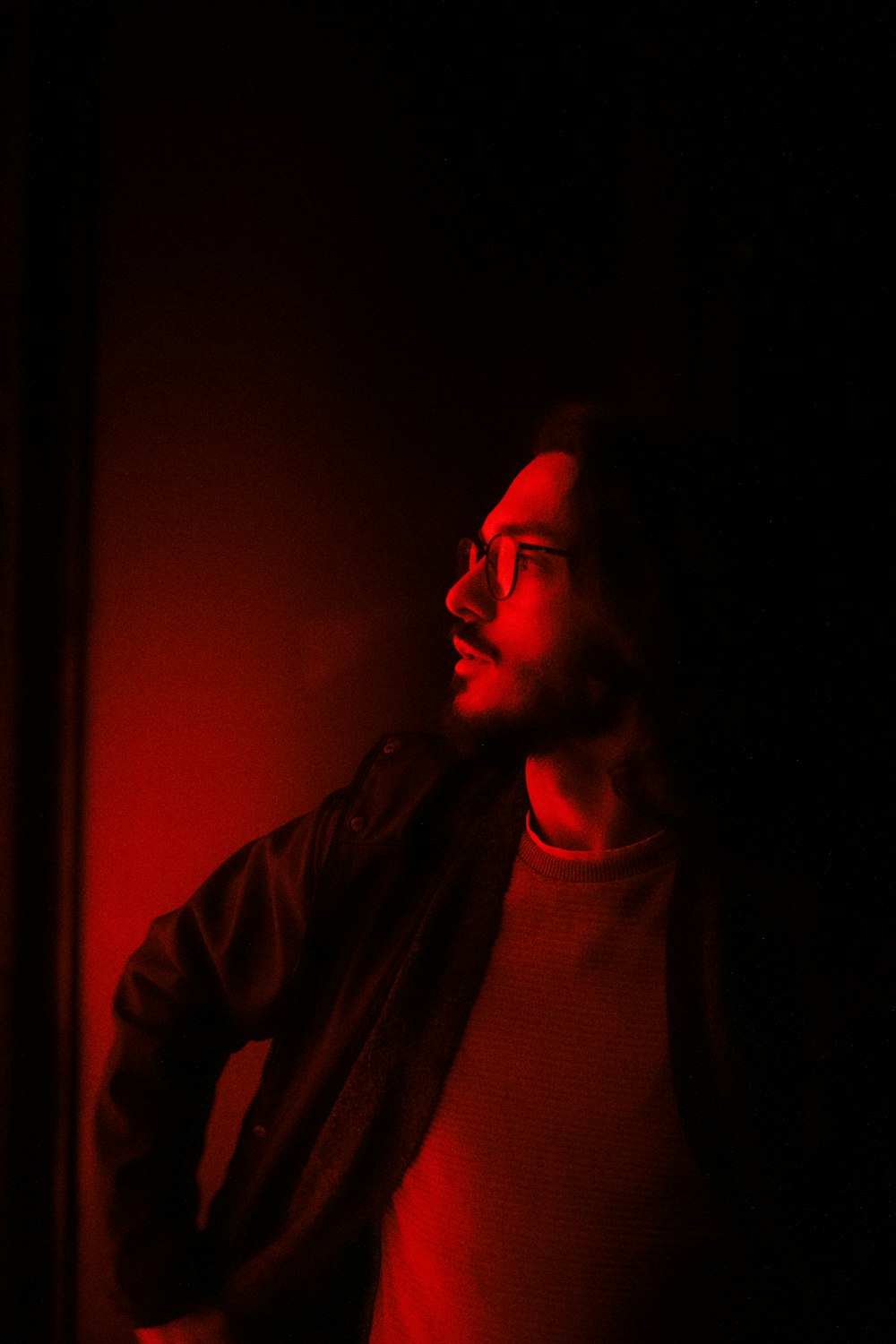 a man standing in a dark room with a red light