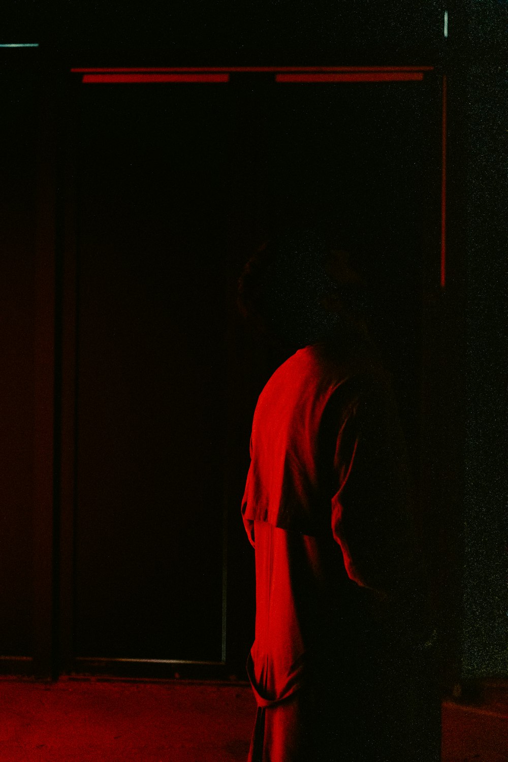 a person standing in a dark room with a red light