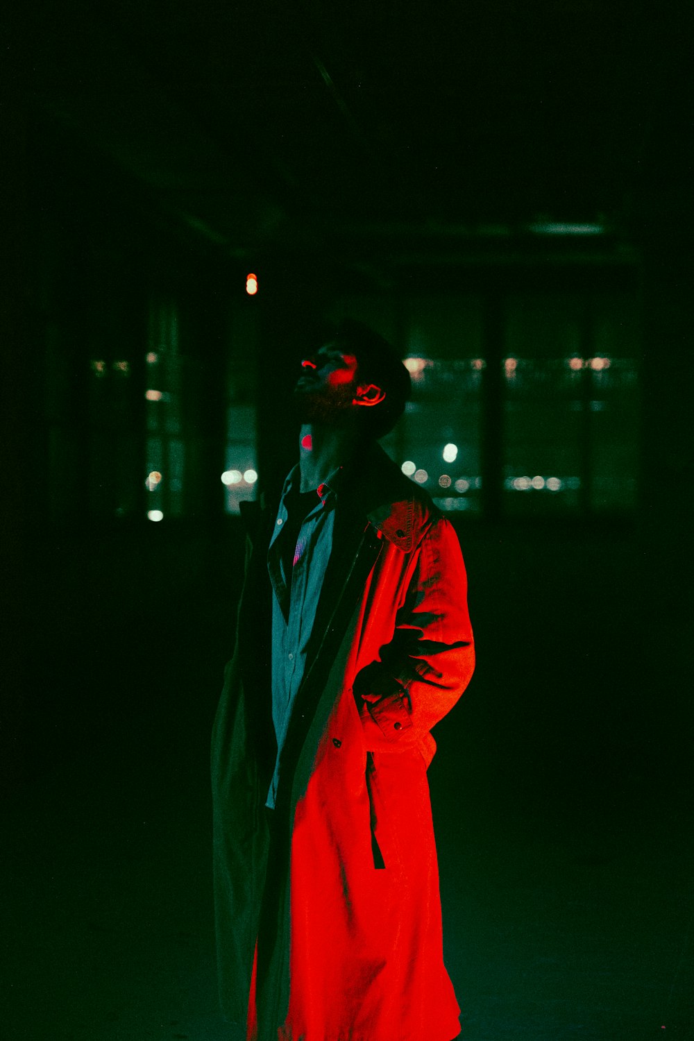 a man standing in the dark wearing a red coat